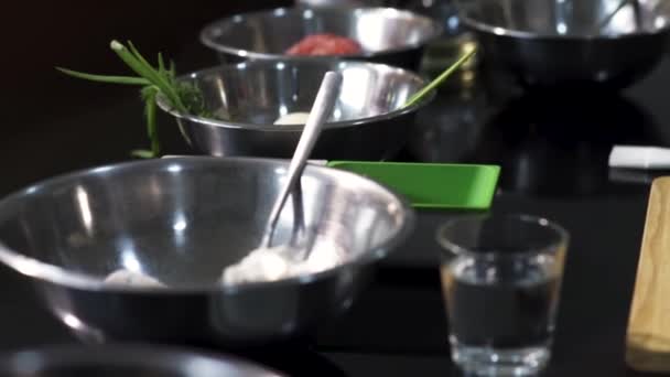 Vista da tavolo con diversi ingredienti in ciotole. Art. Primo piano di piatti profondi di metallo con farina, patate, cipolla verde vicino a un tagliere di legno, concetto di cottura degli alimenti. — Video Stock