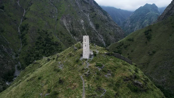 古代の葬儀の建設の空中ビュー大豆ペード,チェチェン共和国,ロシア.行動だ。山に囲まれた緑の丘の上に白い塔. — ストック写真