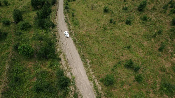 Mit dem einsamen Auto über die Landschaft fliegen. Handeln. Grüne Natur und eine enge Straße mit fahrendem Fahrzeug. — Stockfoto