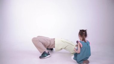 Beyaz bir fotoğraf stüdyosundaki fotoğraf çekiminde güzel, mutlu bir aile. Sahne arkasında. Anne ve kızı oynuyor ve eğleniyorlar..