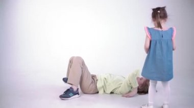 Beyaz bir fotoğraf stüdyosundaki fotoğraf çekiminde güzel, mutlu bir aile. Sahne arkasında. Anne ve kızı oynuyor ve eğleniyorlar..