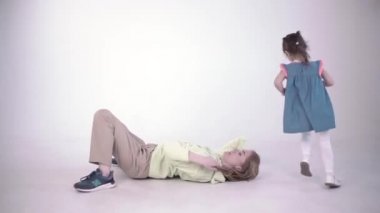 Parlak bir stüdyoda sevimli bir anne ve kızı var. Şarjör. Kadın, çocuğu etrafta koştururken küçük kızına nasıl köprü yapılacağını göstermeye çalışıyor..