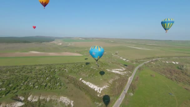 Draufsicht auf das Ballonfestival. Schuss. Schöne Sommerlandschaft mit grünen Wiesen und Luftballonfestival. Bunte Luftballons beim Ballonfestival — Stockvideo