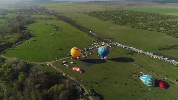 Ovanifrån av ballong festival. Skjuten. Vackert sommarlandskap med gröna fält och ballongfestival. Färgglada ballonger på ballongfestival — Stockvideo