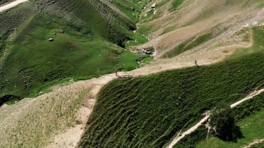Dağlarda nefes kesen doğal manzaradan keyif alan insanların hava görüntüsü. Başla. Yeşil tepeleri kaplayan uzun ve dar kırsal yollar.