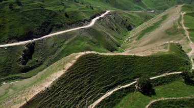 Yeşil dağ vadisinde yaz otlaklarında yürüyüş yapan turistler, hava manzarası. Başla. Yeşil yaz tepesinde yürüyen insanlar, seyahat ve macera kavramı.