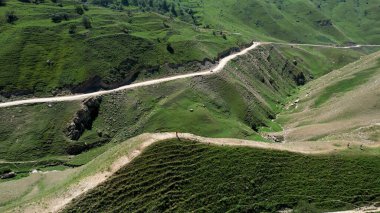 Yeşil dağ vadisinde yaz otlaklarında yürüyüş yapan turistler, hava manzarası. Başla. Yeşil yaz tepesinde yürüyen insanlar, seyahat ve macera kavramı.