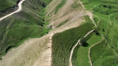 Yeşil dağ vadisinde yaz otlaklarında yürüyüş yapan turistler, hava manzarası. Başla. Yeşil yaz tepesinde yürüyen insanlar, seyahat ve macera kavramı.