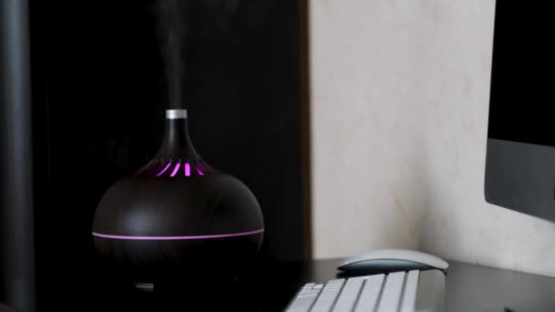 Humidifier spreading steam at home, details of the a modern apartment interior. Concept. Ultrasonic humidifier standing on a table near computer and keyboard. — Stock Video