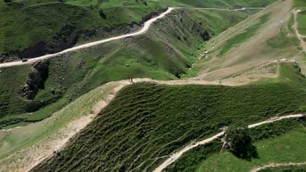 Vista aérea de personas disfrutando de un impresionante paisaje natural en las montañas. Acción. Largos caminos rurales estrechos con curvas que cubren colinas verdes. — Vídeo de stock