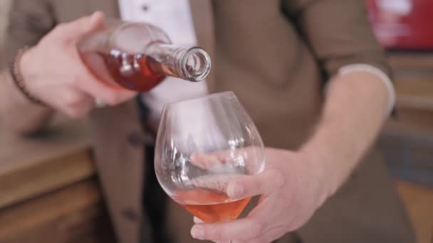 ベージュのスーツに身を包んだ男が、透明なガラスの中にワインを注ぐ。行動だ。バーでフルーツワインを注ぐ男性ソムリエ. — ストック動画