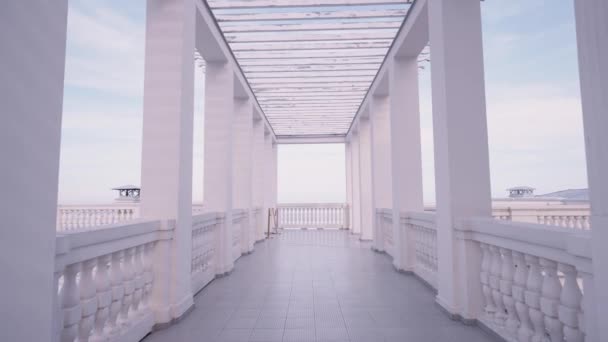 Das Gehen zwischen weißen Marmorsäulen schafft einen schönen Korridor vor blauem Himmel Hintergrund. Handeln. Marmor schöne Seebrücke an einem Sommertag. — Stockvideo