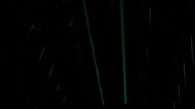 Siyah arka planda izole edilmiş, neon ışıklı sütunları ve ışınları olan karanlık bir uzay. Tasarım. Karanlık uzayda aydınlık sütunlar ve ışınlarla ortaya çıkan ve kaybolan düz renkli çizgiler.