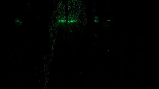 Абстрактний силует чоловічих ніг, що йдуть через темний коридор з зеленими сяючими частинками. Дизайн. Чоловік супергерой, що поширює зелену енергію . — стокове відео