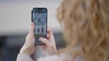 Rusya, MOSCOW - 27 Eylül 2021: Kadın telefonda binanın fotoğraflarını çekiyor. Başla. Kadın telefonu tutuyor ve binanın fotoğraflarını çekiyor. iPhone 13 'ün yeni gelişmiş kamerası