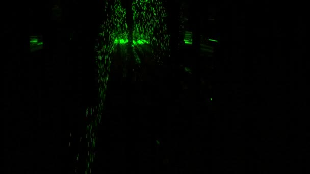 Silueta abstracta de patas masculinas caminando por el oscuro corredor con partículas verdes brillantes. Diseño. Un hombre superhéroe esparciendo energía verde. — Vídeos de Stock