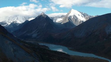 Breathtaking view of a mountain range with snowy peaks and a turquoise lake reflecting the sky. Media