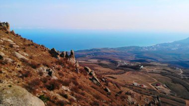 Arka planda çarpıcı bir deniz manzarası olan Demerdzhi dağ sırasının üzerinde uçan hava aracı. Medya