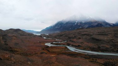 Winding river flowing through a scenic valley towards majestic misty mountains in patagonia. Media