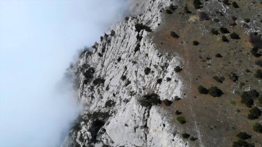Bulutların ve sisin Drone görüntüsü güzel ve vahşi bir dağ zirvesinin üzerinde hareket ediyor. Medya
