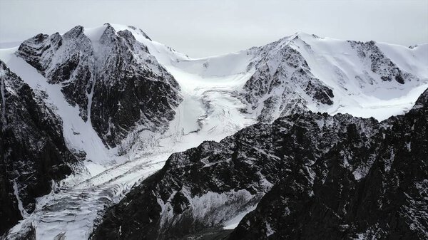 Snow covered peaks and a glacier dominate the landscape. Media