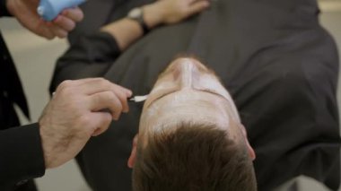 Profesyonel makyaj sanatçısı, performanstan önce beyaz temeli bir adamın yüzüne uygular. Kırp