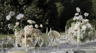 Düğün masası çiçeklerle süslenmiş ve bahçe düzeninde mumlarla süslenmiş. Eylem