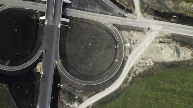 Nehir üzerinde bir otoyol kavşağının inşaatı farklı gelişim aşamalarını gösterir.