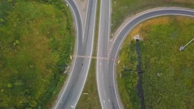 Yol boyunca giden araçlar ve kamyonlarla bir otoyol kavşağının havadan aşağı görüntüsü. Kırp