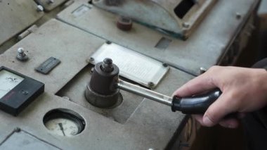 Mans eski, tozlu bir endüstriyel makine kontrol panelinde göstergeleri olan bir manivela kullanıyordu. Kırp