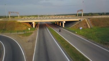 İHA görüntüsü, köprünün altından geçen boş bir otoyolda giden bir motosikletlinin görüntüsü. Kırp