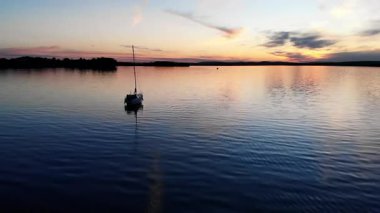 Güzel ve renkli bir akşamın günbatımında sakin sularda yüzen yelkenli.