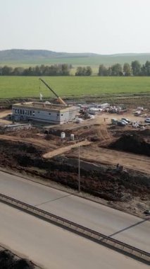 İnşaat işçileri otoyolun yakınına vinç kaldırma malzemeleri ile yeni bir yapı inşa ediyorlar.