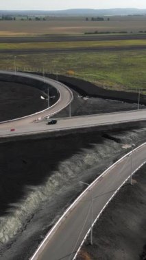 İnşaat işçileri yeni bir otoyol kavşağı inşa ediyorlar, geniş tarlalar arasında yolları birleştiriyorlar.