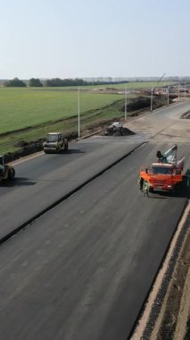 İşçiler ve makineler kırsal alanda yeni bir asfalt otoyol inşa ediyorlar.