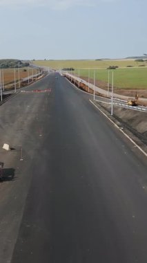 Yeni bir otoyola asfalt döşeyen ve sokak lambaları takan yol işçileri