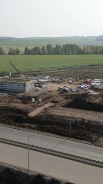 İnşaat işçileri kırsal bir alanda otoyolun yakınında bir yapı inşa ediyorlar.