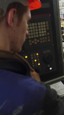 Fabrika işçisi, sanayi ortamında metal parçaları üreten bir cnc makinesi çalıştırıyor.
