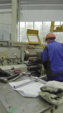 Torna makinesi çalıştıran fabrika işçisi, metal parçaları üretiyor.
