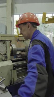 Metal parçası üretmek için torna makinesi kullanan fabrika işçisi.