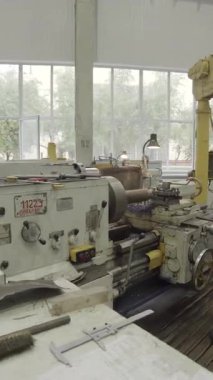 Torna makinesi işleten yetenekli bir fabrika işçisi, işlek bir fabrikada metal parçaları üretiyor.