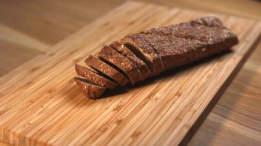 Doğal bambu kesim tahtasının üzerinde duran tohumlu taze dilimlenmiş tam tahıllı ekmek. Medya