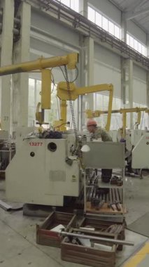 Torna makinesi çalıştıran fabrika işçisi yoğun bir endüstriyel ortamda metal parçaları üretiyor.