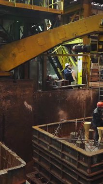 Dökümhane işçileri metal döküm için bir kalıp hazırlıyorlar. Endüstriyel imalatta güvenliği ve hassasiyeti sağlıyorlar.