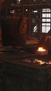 Dökümhane işçileri büyük bir endüstriyel fabrikada erimiş metali kalıplara döküyorlar.