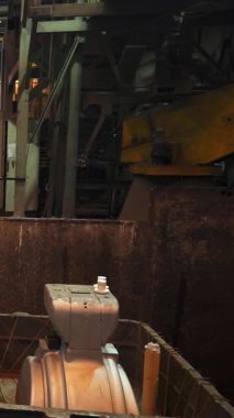 Dökümhanede endüstriyel robotik koldan erimiş metal kalıba dökülüyor