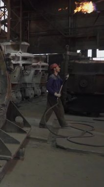 Dökümhane işçileri bir metal döküm fabrikasında ağır makineler kullanarak erimiş metali kalıplara döküyorlar.