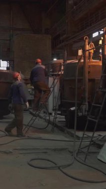 Dökümhane işçileri ağır sanayi ortamında erimiş metali kalıba döküyorlar.