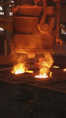 Dökümhane işçileri yoğun endüstriyel ortamda erimiş metali kalıplara dikkatlice döküyorlar.