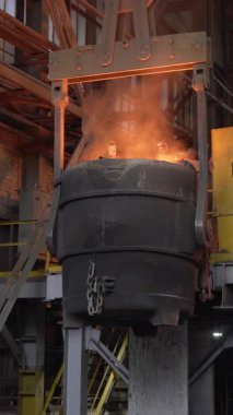 Erimiş çelik kepçe endüstriyel vinçle taşınıyor.